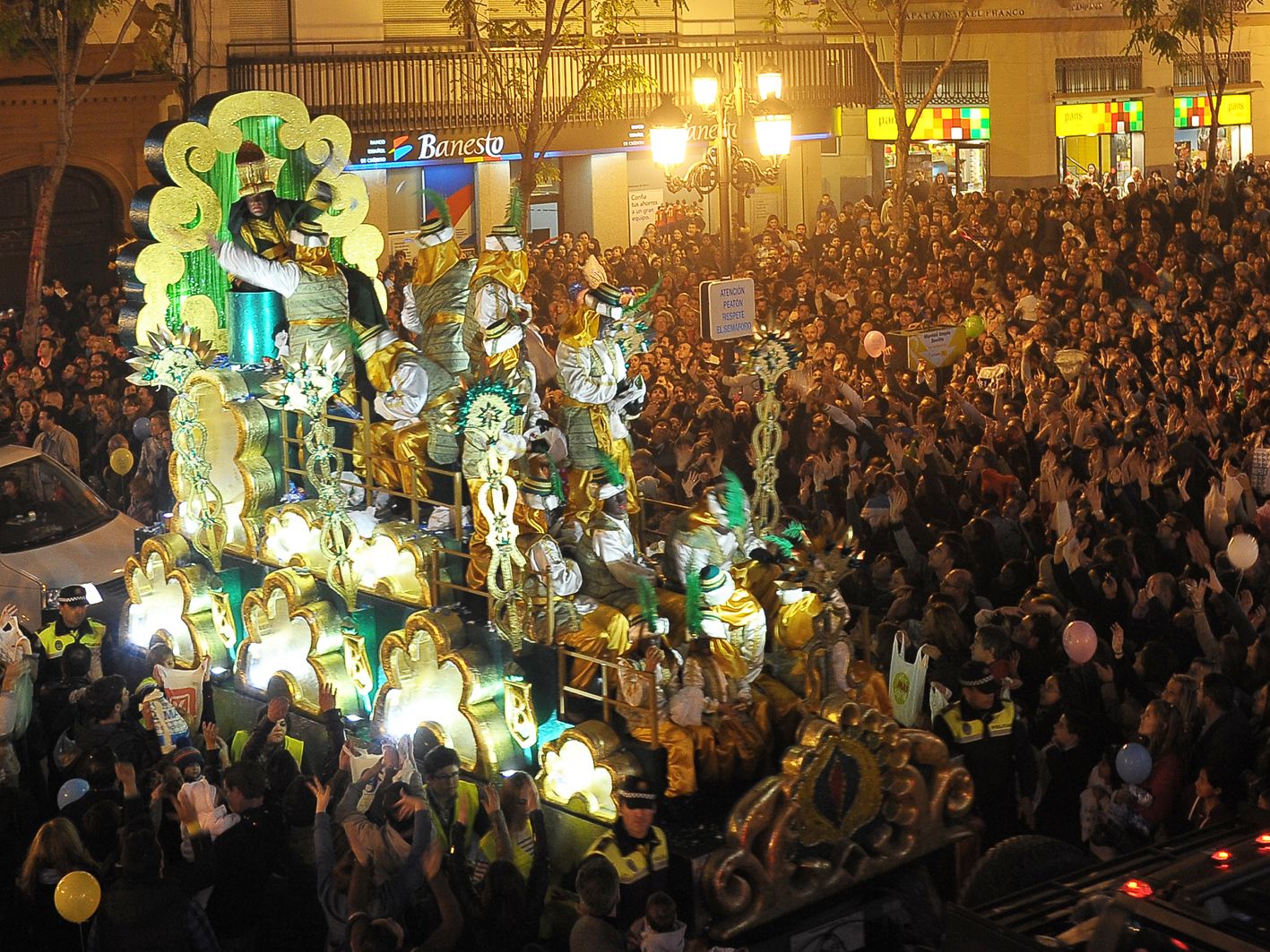 Carroza de un Rey Mago de la Cabalgata del Ateneo de Sevilla entre una multitud, en 2013