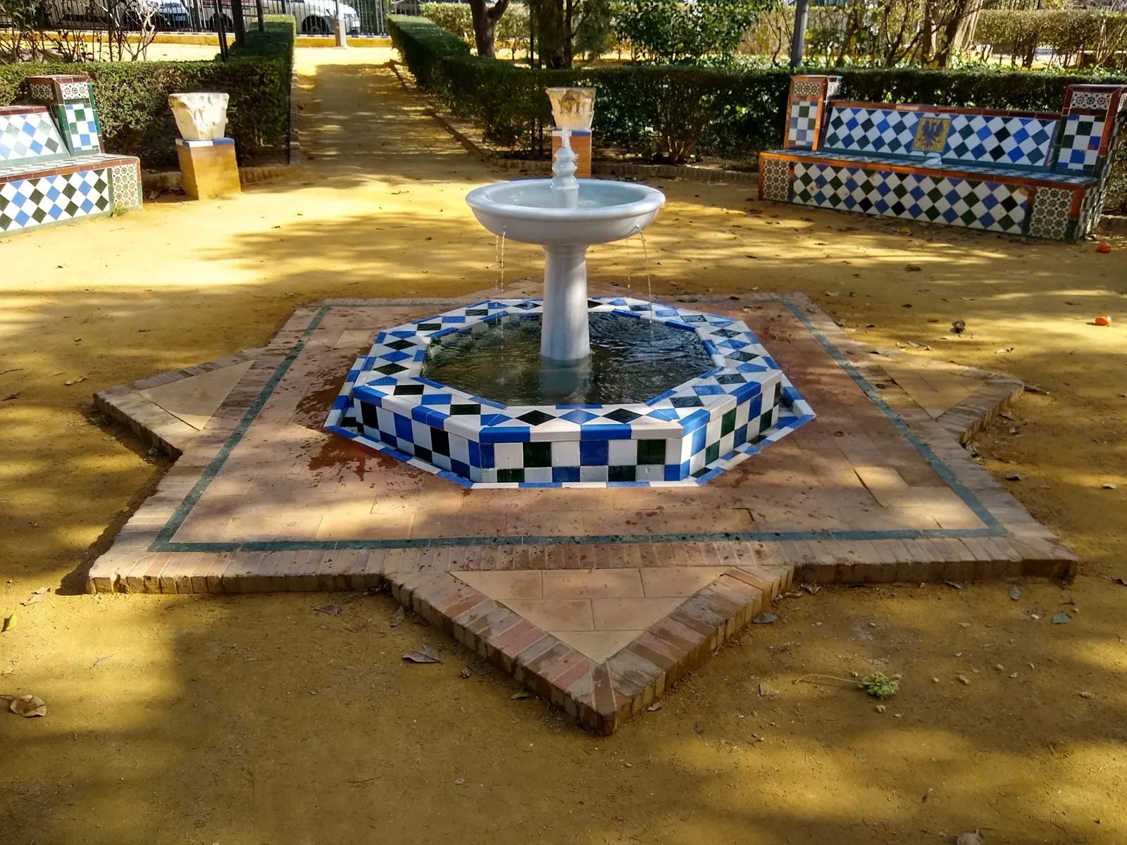 Fuente de azulejos entre bancos de cerámica en los Jardines de Murillo, en Sevilla, donde se instala la Feria del Libro.