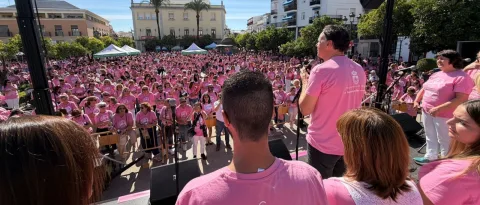 Una multitud con camisetas rosas llena una plaza desde un escenario donde habla un hombre.